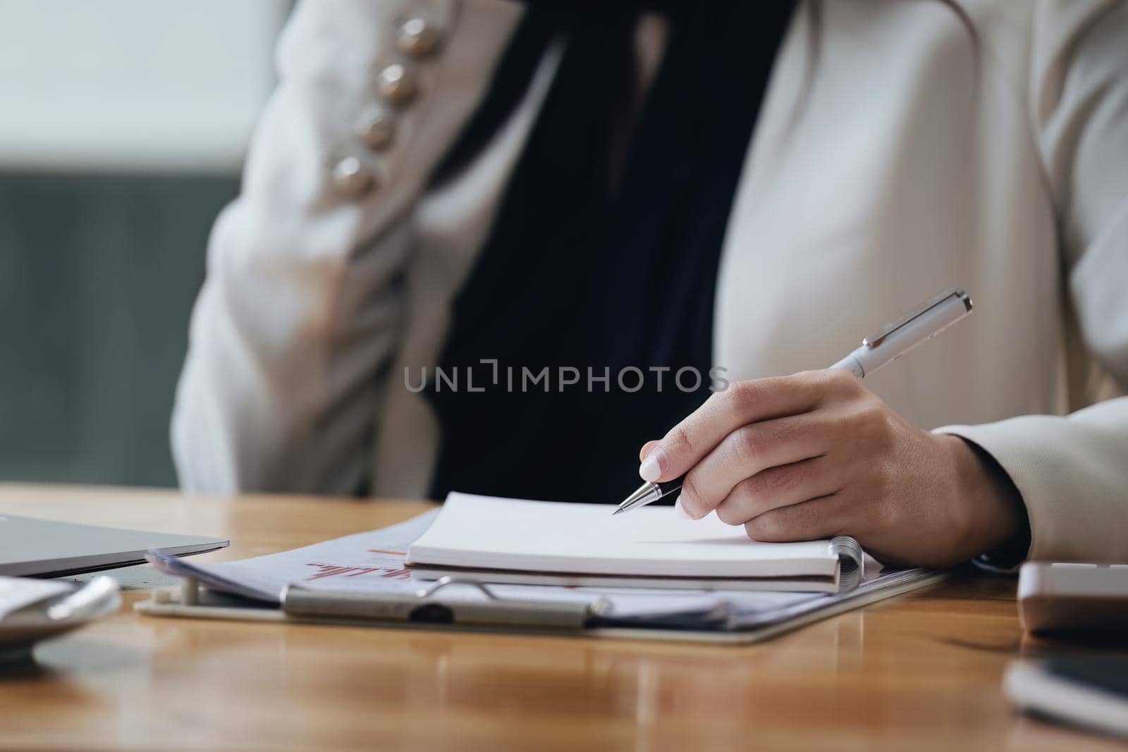 Asian businesswoman taking business notes while talking on the phone by Manastrong