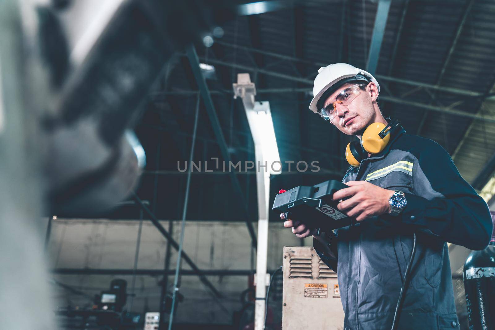 Young factory worker working with adept robotic arm in a workshop . Industry robot programming software for automated manufacturing technology .