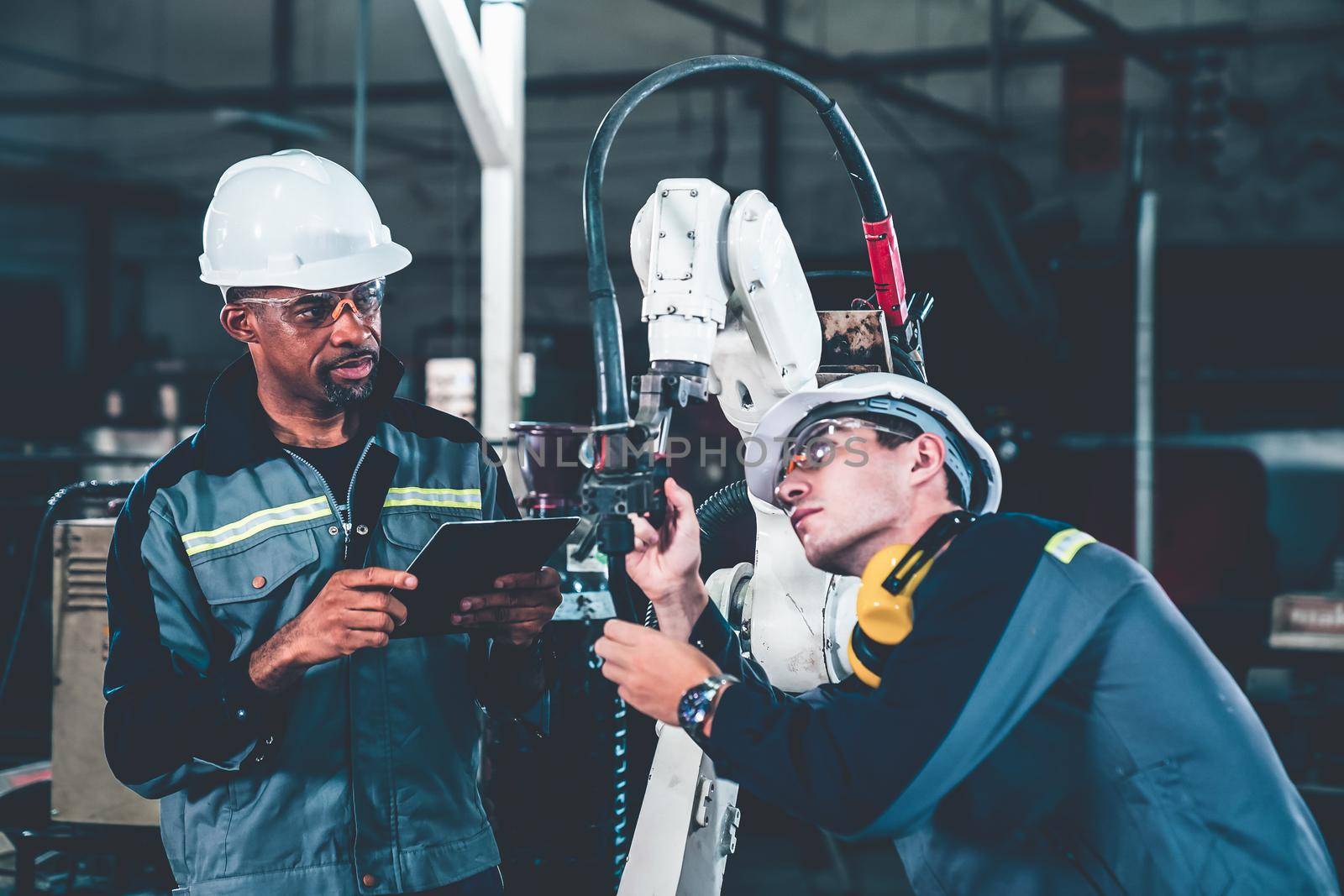 Factory workers working with adept robotic arm in a workshop by biancoblue