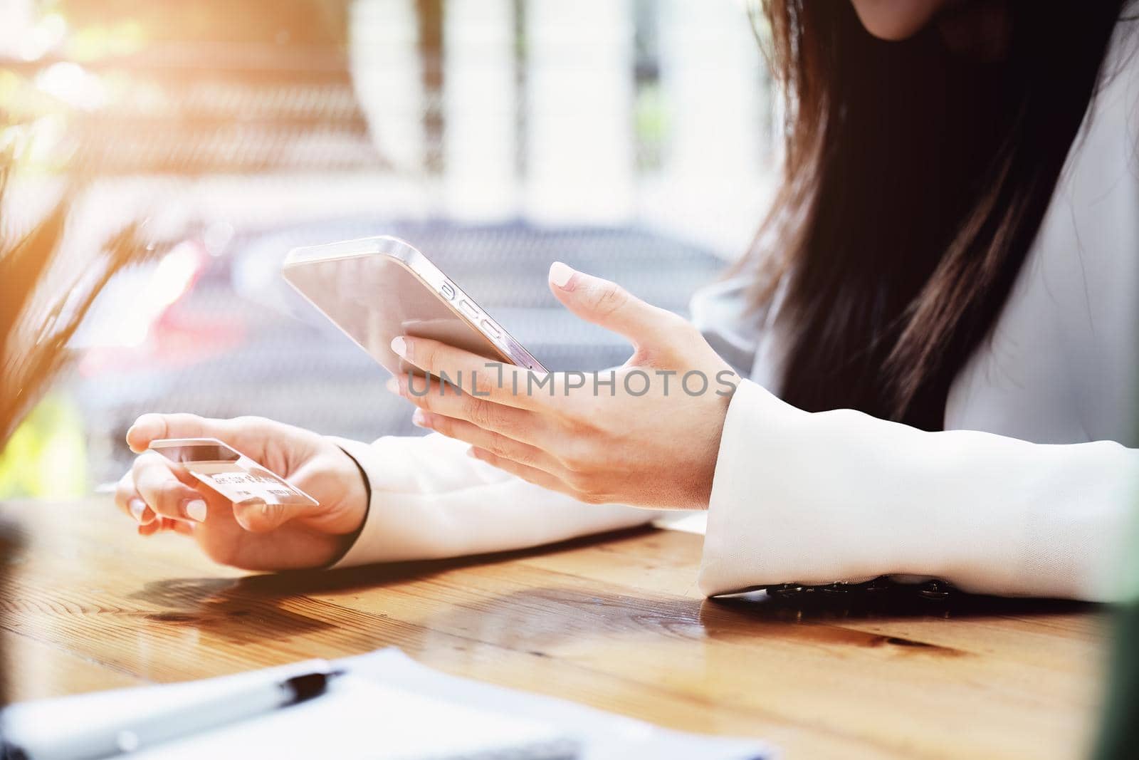 Asian young woman using a mobile phone and credit card for online shopping by Manastrong