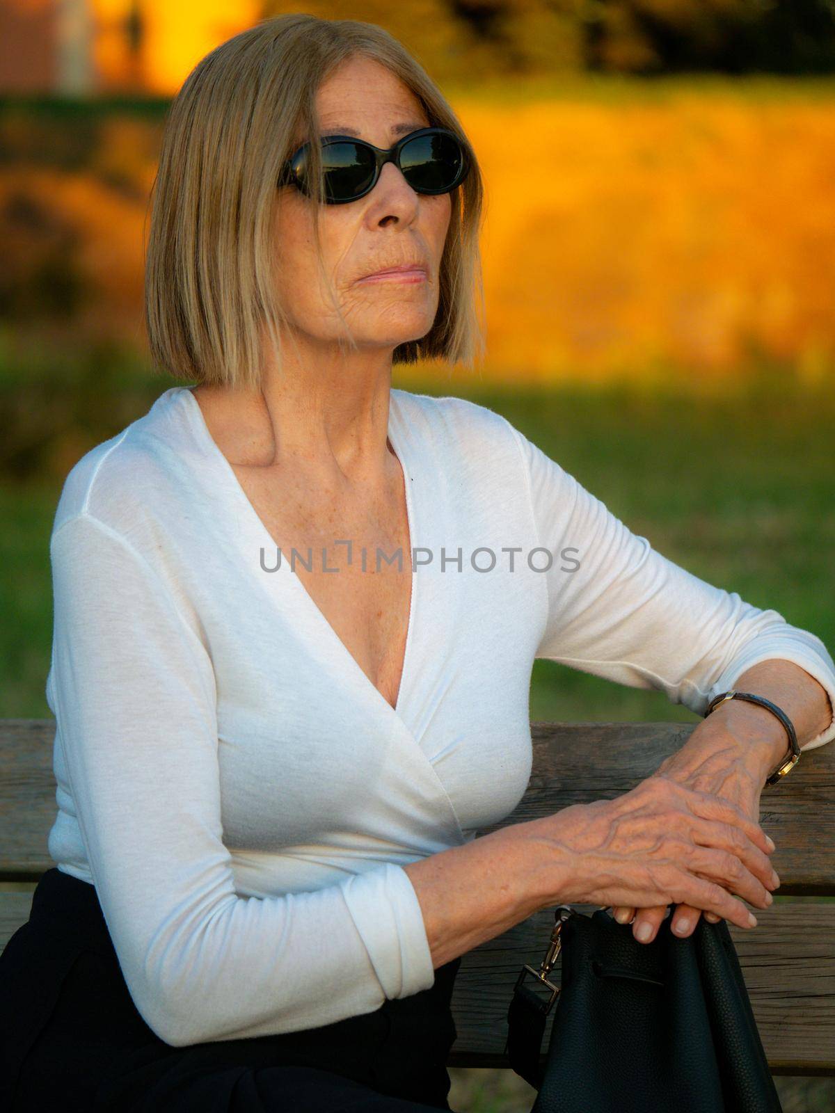 senior fit elegant lady dressed blaka dn white wearing sunglasses enjoying nature in summer