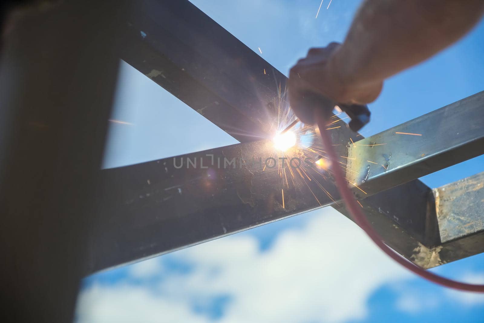 The contractor is using an electric grinder to decorate the steel welding point. by Manastrong