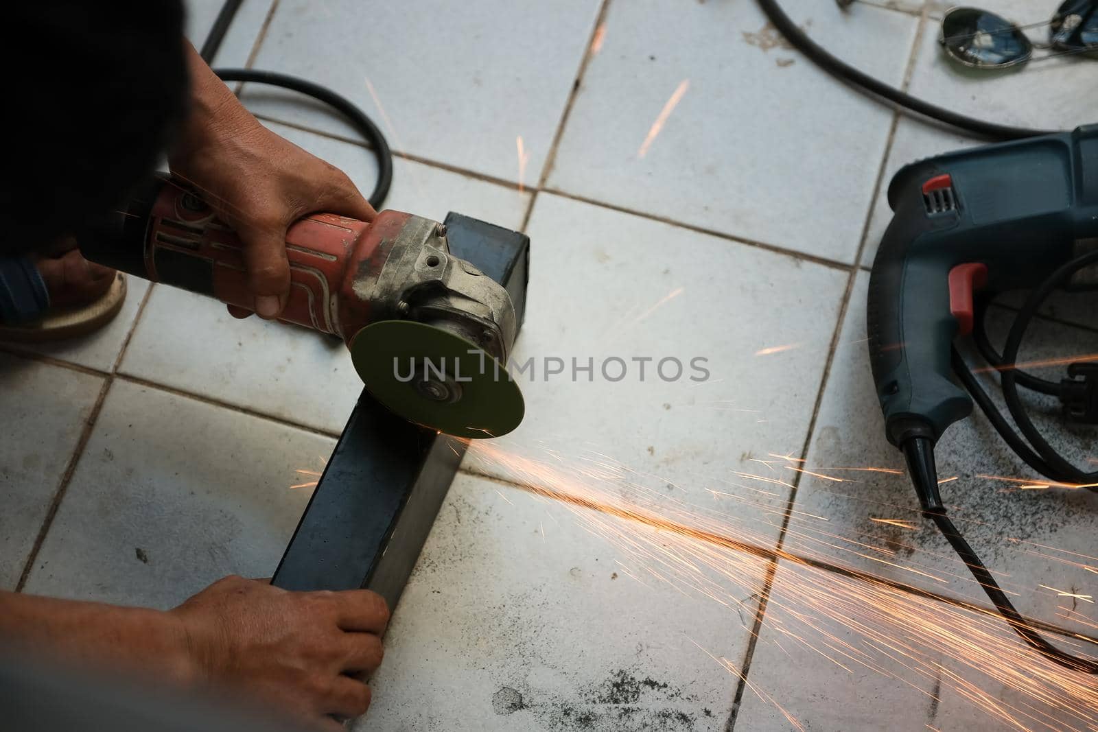 The contractor is using an electric grinder to decorate the steel welding point. by Manastrong