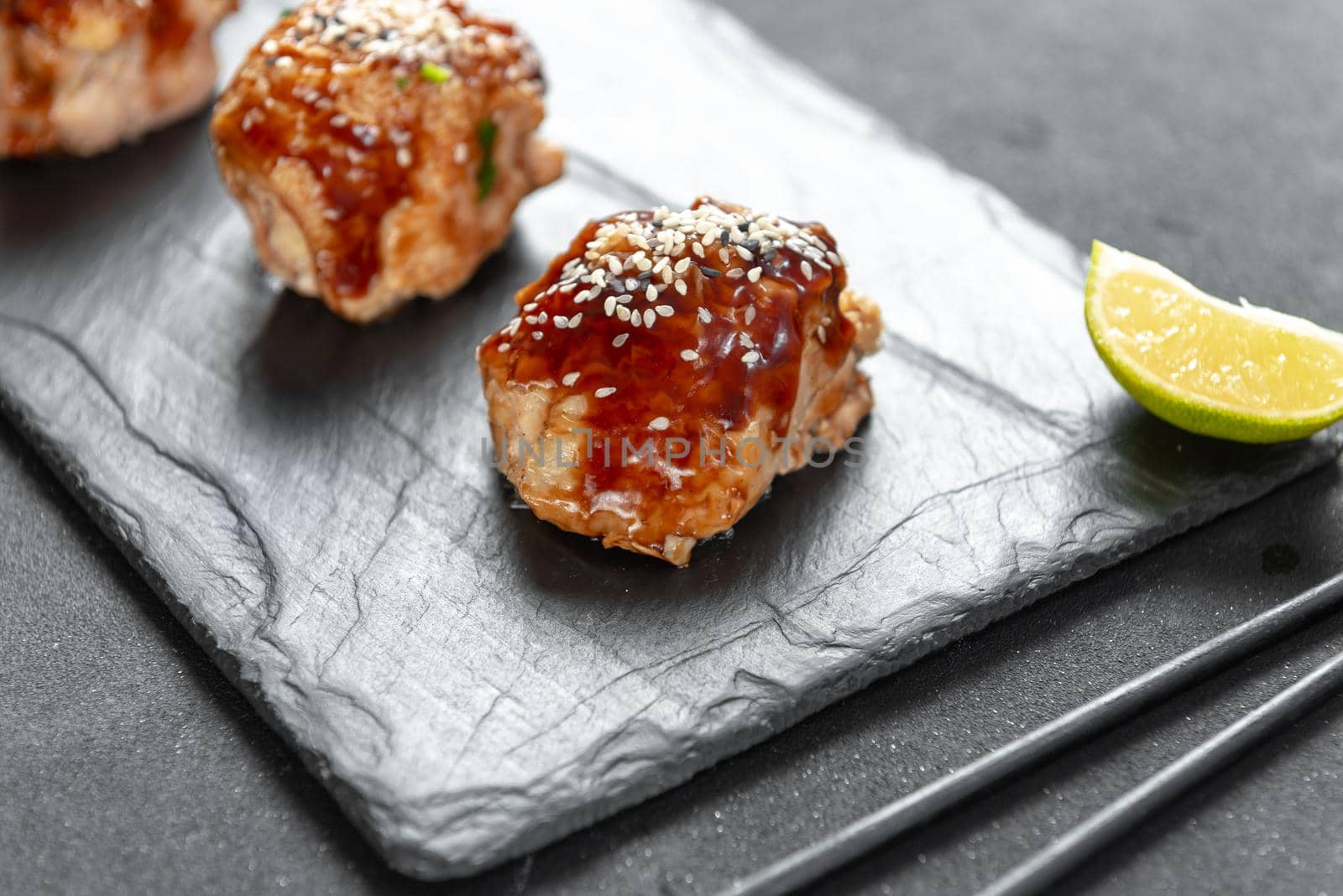 teriyaki chicken on a slate with sesame seeds. Asian Cuisine by gulyaevstudio