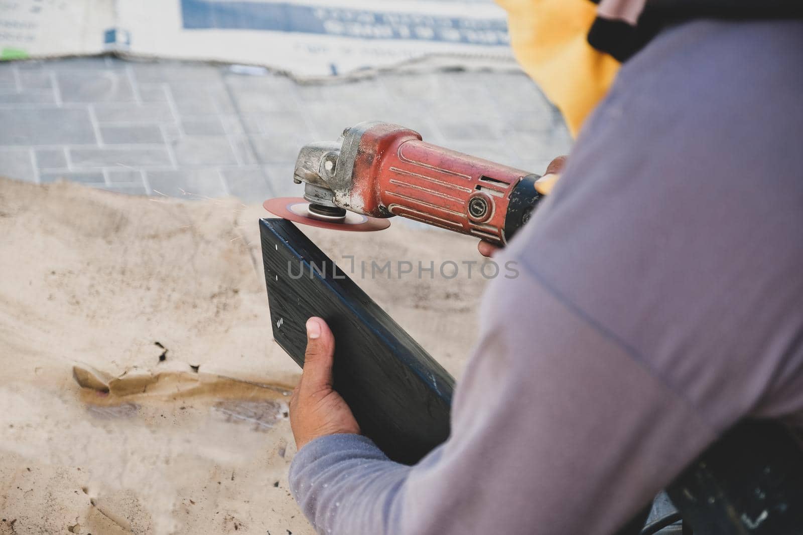 The contractor is using an electric grinder to decorate the steel welding point.