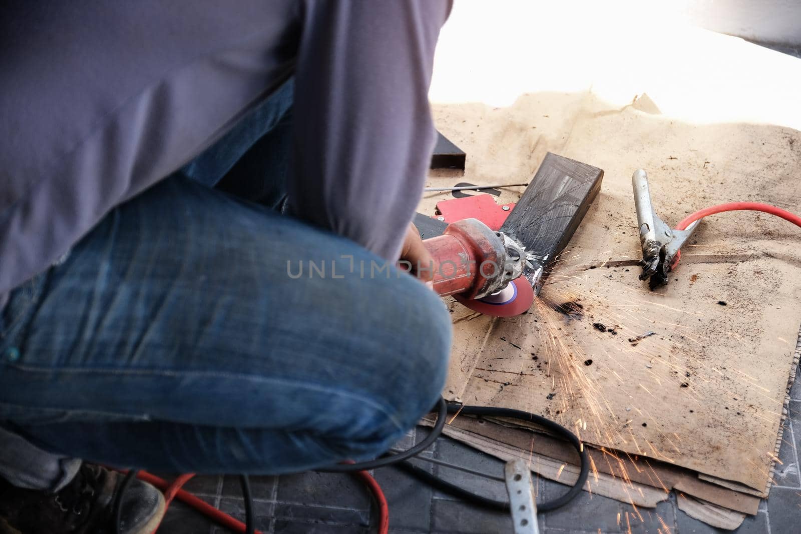 The contractor is using an electric grinder to decorate the steel welding point.