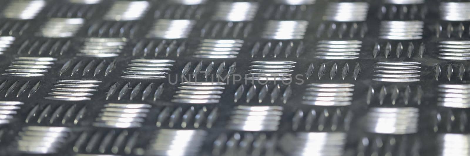 Close-up of seamless metal floor plate with diamond pattern, antislip stainless steel sheet. Ribbed silver notched metal sheet with texture. Grunge concept