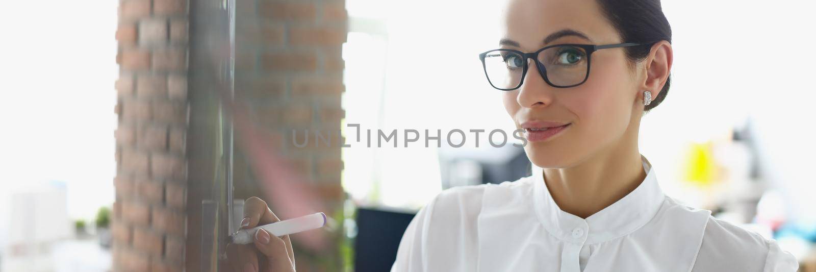 Portrait of businesswoman make notes on board with goals for next year, preparing report of done work. Office worker in presentable suit. Business concept