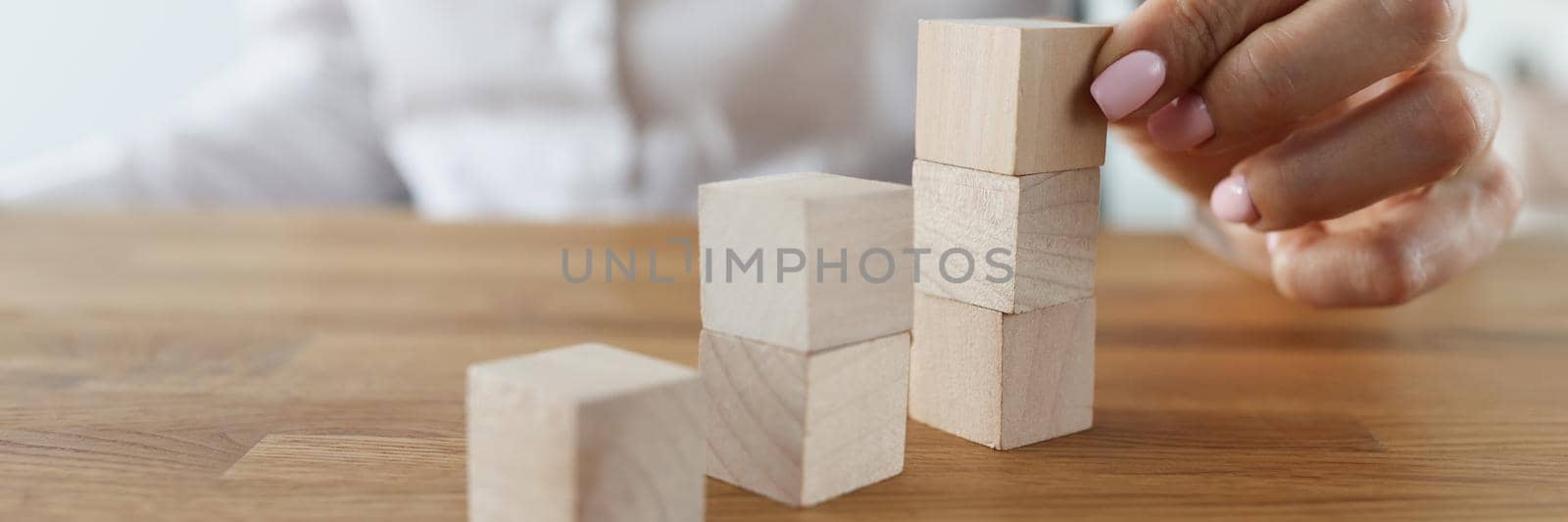 Female put wooden brick on top of another, symbol of building plans by kuprevich