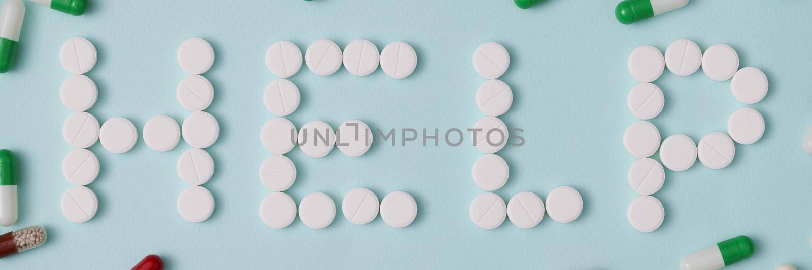 Top view of help lettering made with white round pills, pharmaceutical medicament, oral tablets. Jelly capsules scattered around. Medicine, health concept