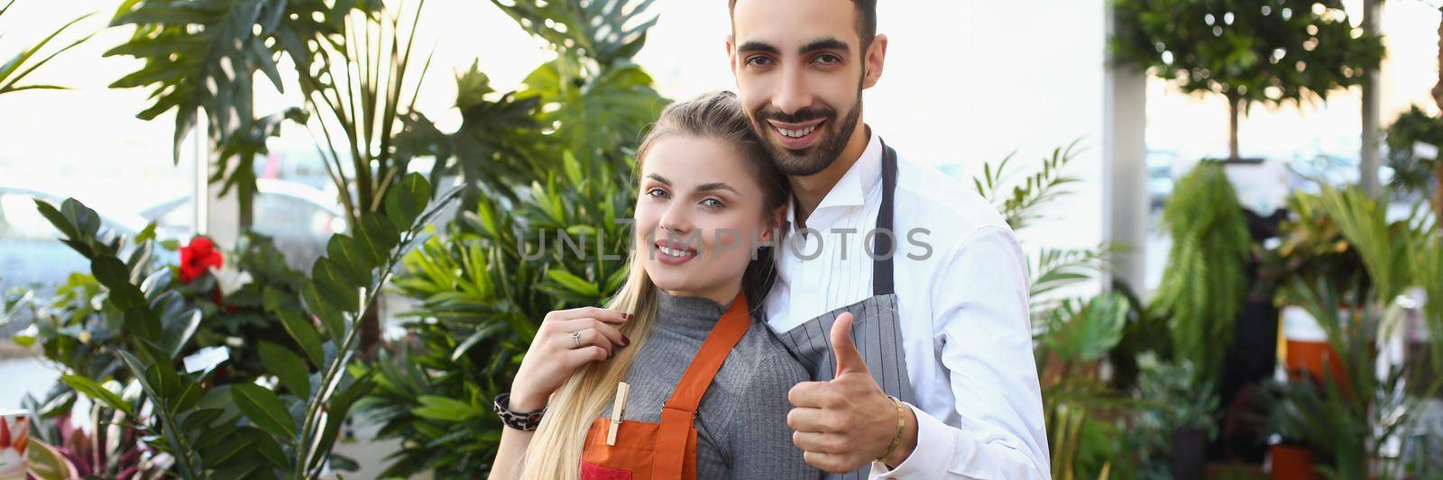 Portrait of young male and female consultants work in flower delivery shop and sale indoor plants. Business, floral design, creative studio, nature concept