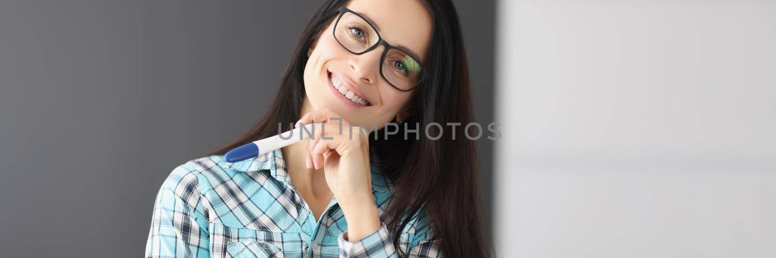 Portrait of young happy female hold pregnancy test, female got big news and smiling. Woman shine with happiness. Pregnancy, new period, life change concept