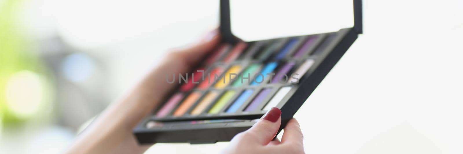 Close-up of makeup artist holding beauty cosmetic product, female hands with colorful eye shadow palette. Visagist tools, beauty, mua, creativity concept