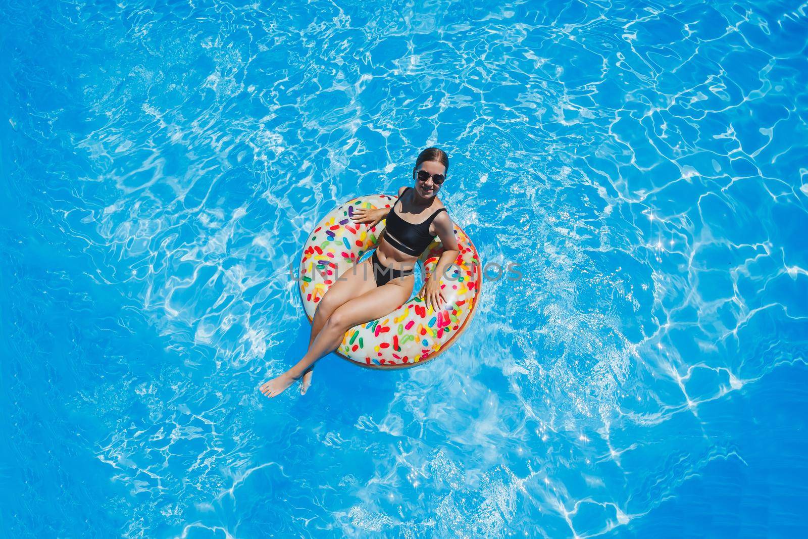 Beautiful woman in sunglasses in the pool floats on an inflatable swimming ring in a black swimsuit, summer photo, swimming photography, summer woman photos by Dmitrytph