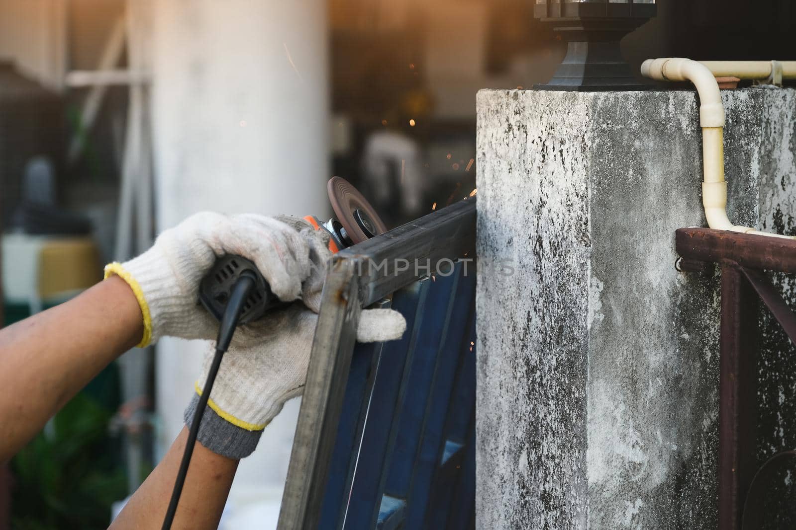 The contractor is using an electric grinder to decorate the steel welding point. by Manastrong