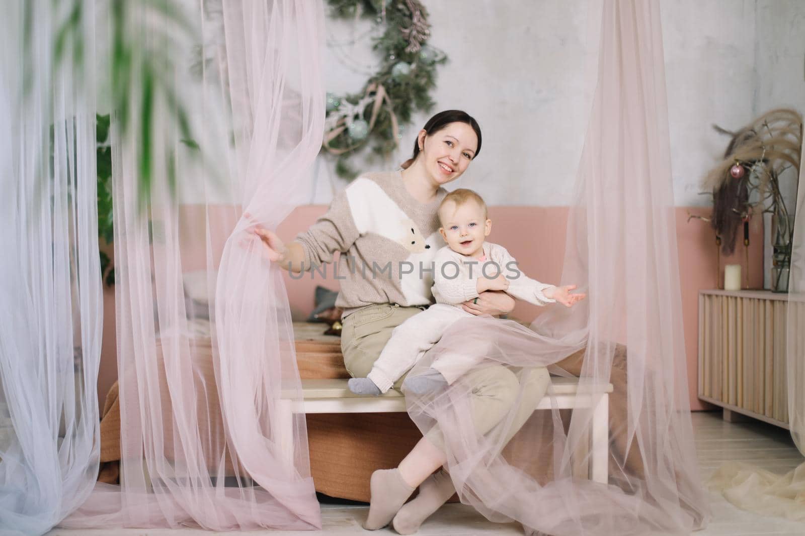 Young mother holding her baby in the bedroom.