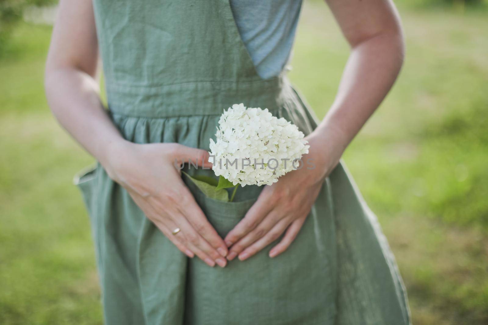 young woman in apron holding flowers in the garden in summer. gardening and profession concept