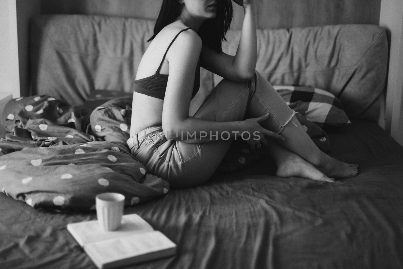 Young sexy woman portrait in bed with a book and coffee cup in the morning