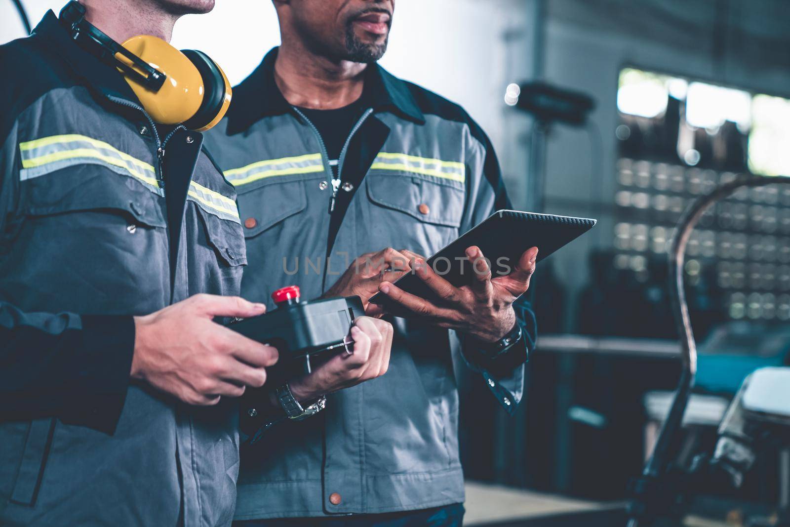 Group of factory job workers using adept machine equipment in a workshop by biancoblue