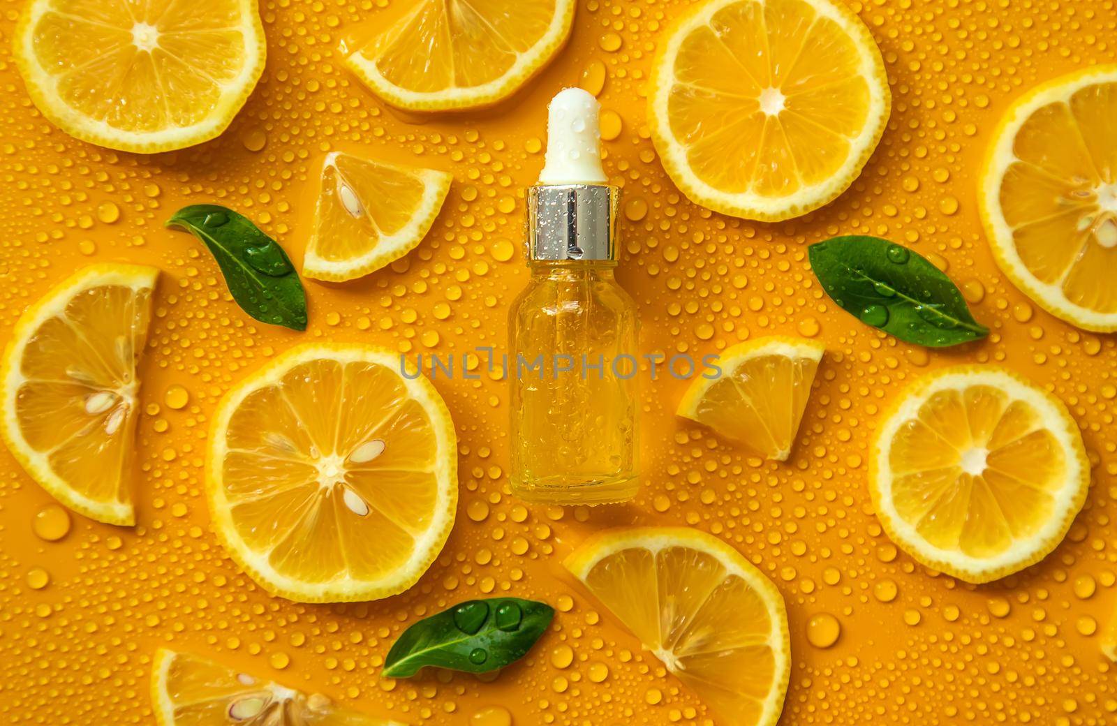 Bottle of cosmetics and drops of liquid, moisturizing lemon. Hyaluronic acid. Selective focus. by yanadjana