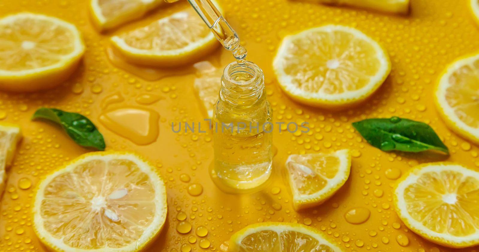 Bottle of cosmetics and drops of liquid, moisturizing lemon. Hyaluronic acid. Selective focus. by yanadjana