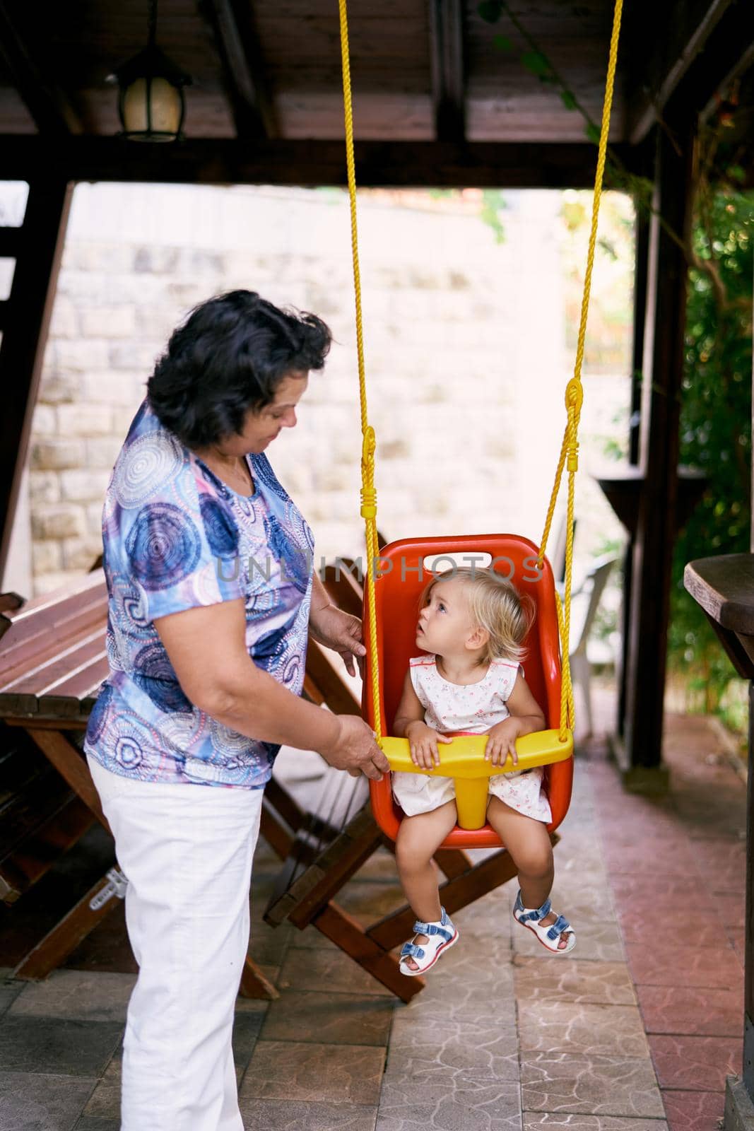 Grandmother swings a little girl on a swing. High quality photo