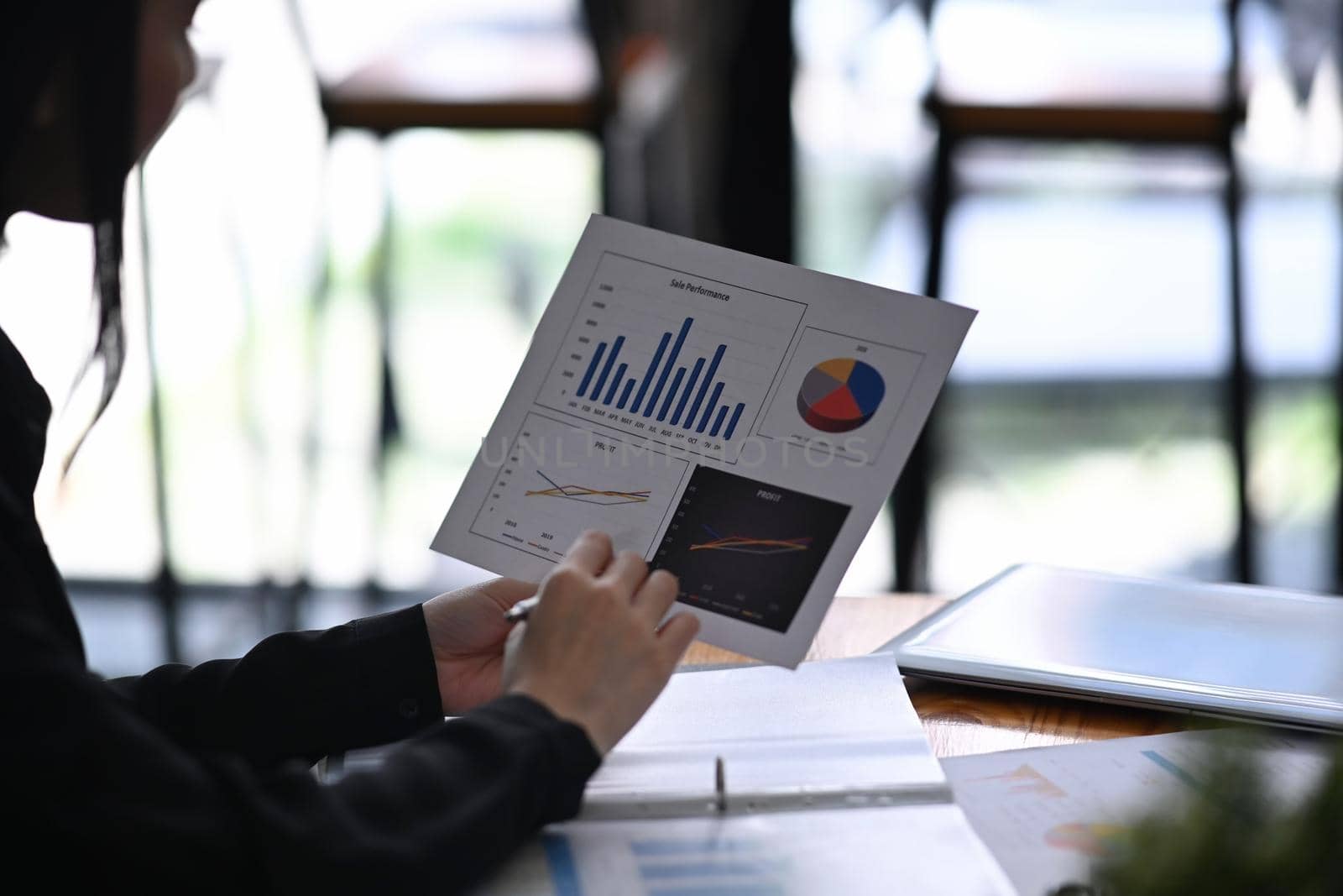 Cropped shot businesswoman analyzing financial graph at office desk.