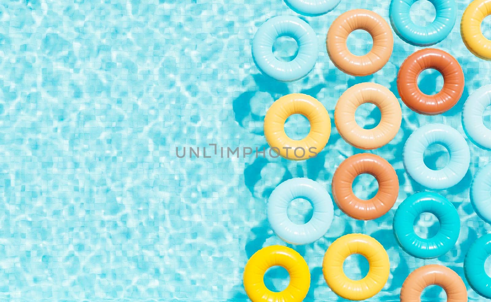 Colorful swim tubes in pool on sunny day by asolano