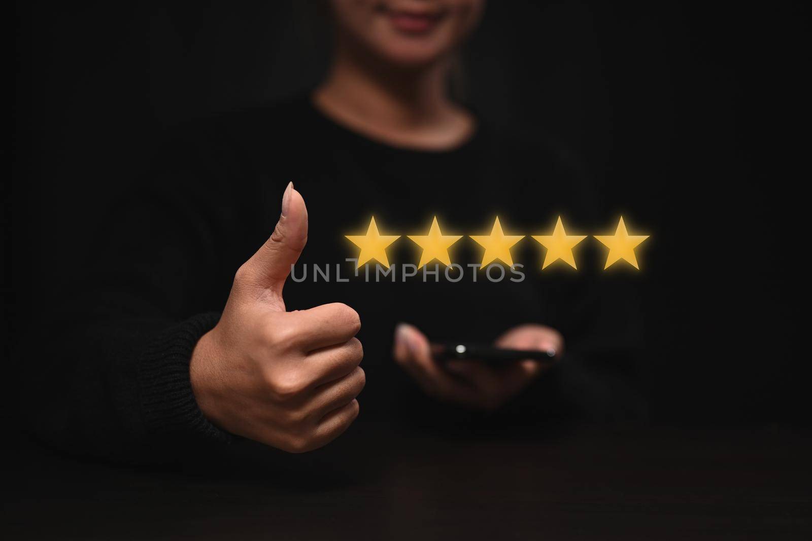 Happy young woman showing thumb up with gold five star icon for giving best score point to review. by prathanchorruangsak