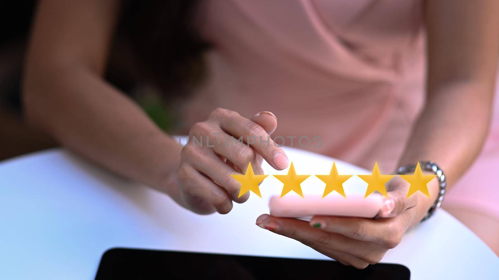 Young woman hand pressing on smartphone screen with gold five star rating feedback icon. by prathanchorruangsak