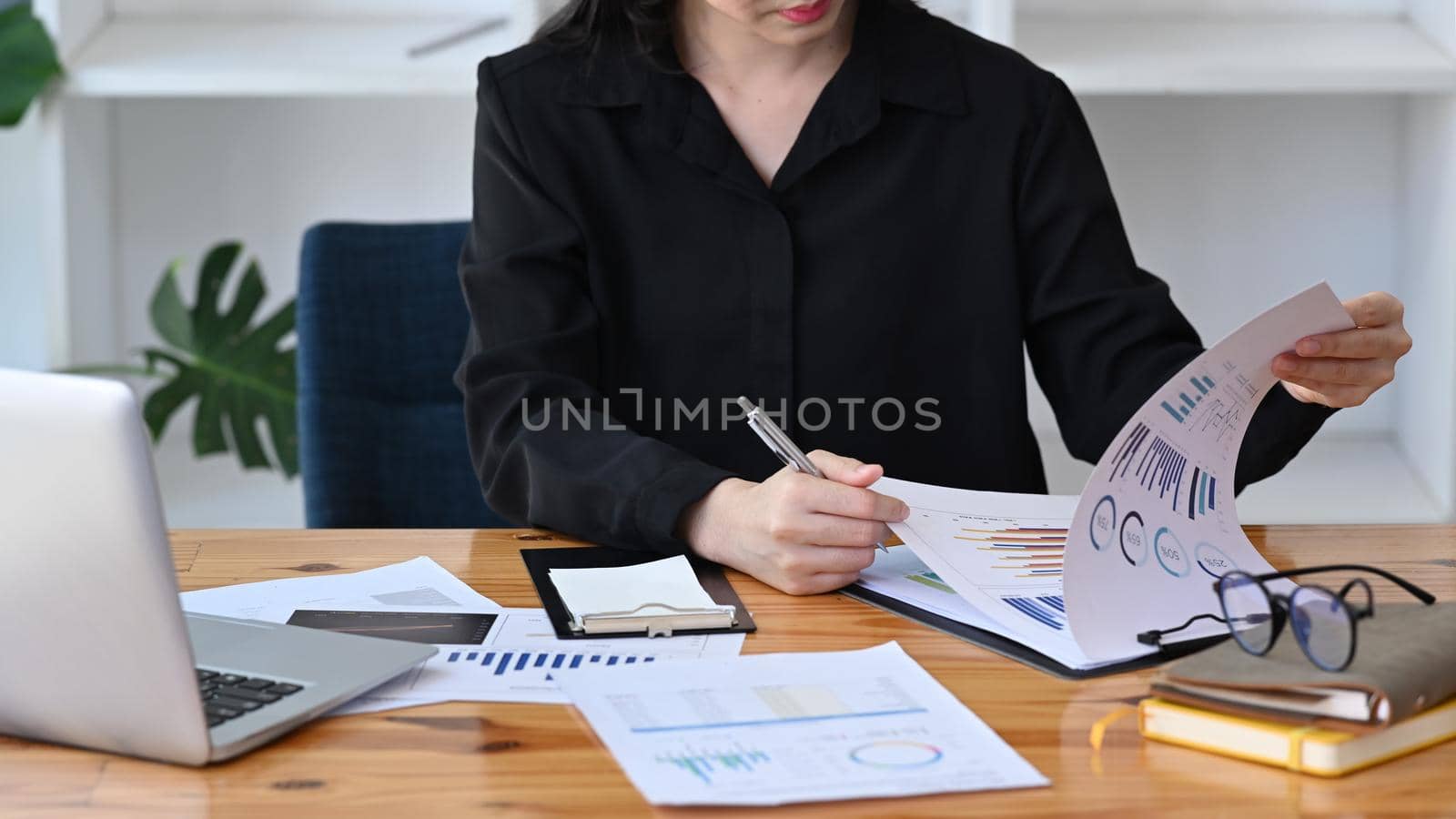 Cropped shot thoughtful businesswoman checking financial reports on office desk. by prathanchorruangsak