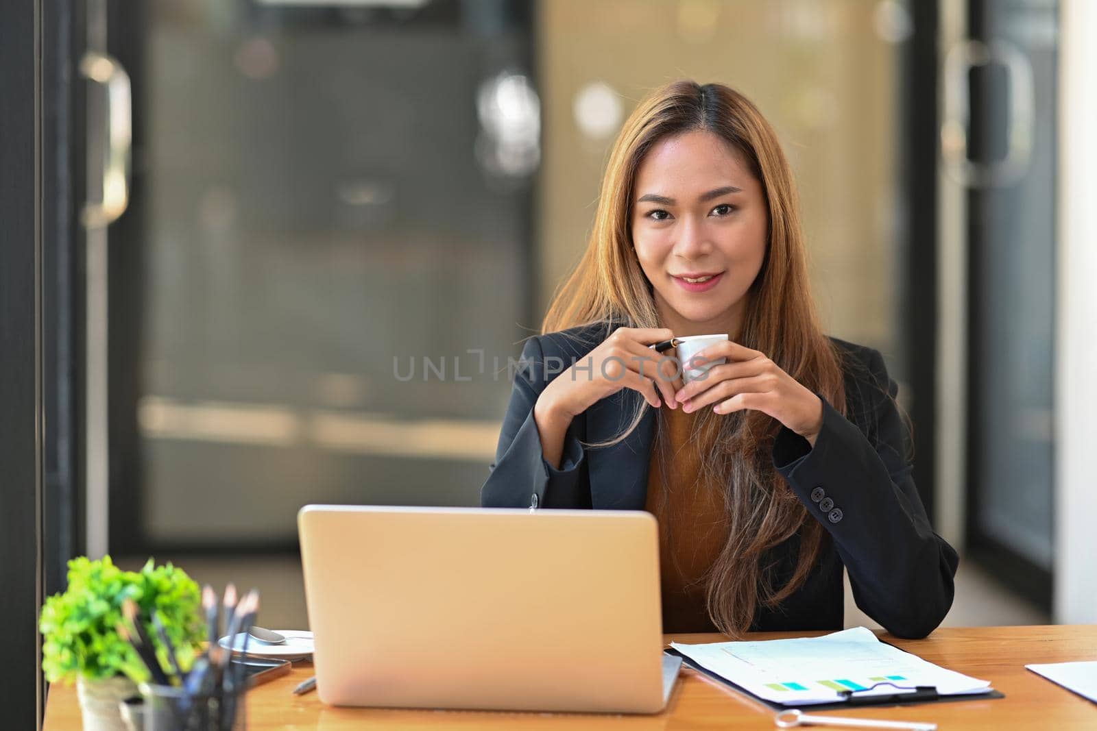 Beautiful businesswoman holding coffee cup and smiling to camera.