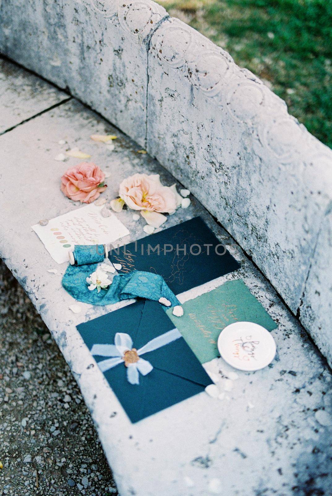 Navy blue wedding envelopes with ribbons and flowers lie on a tile. High quality photo