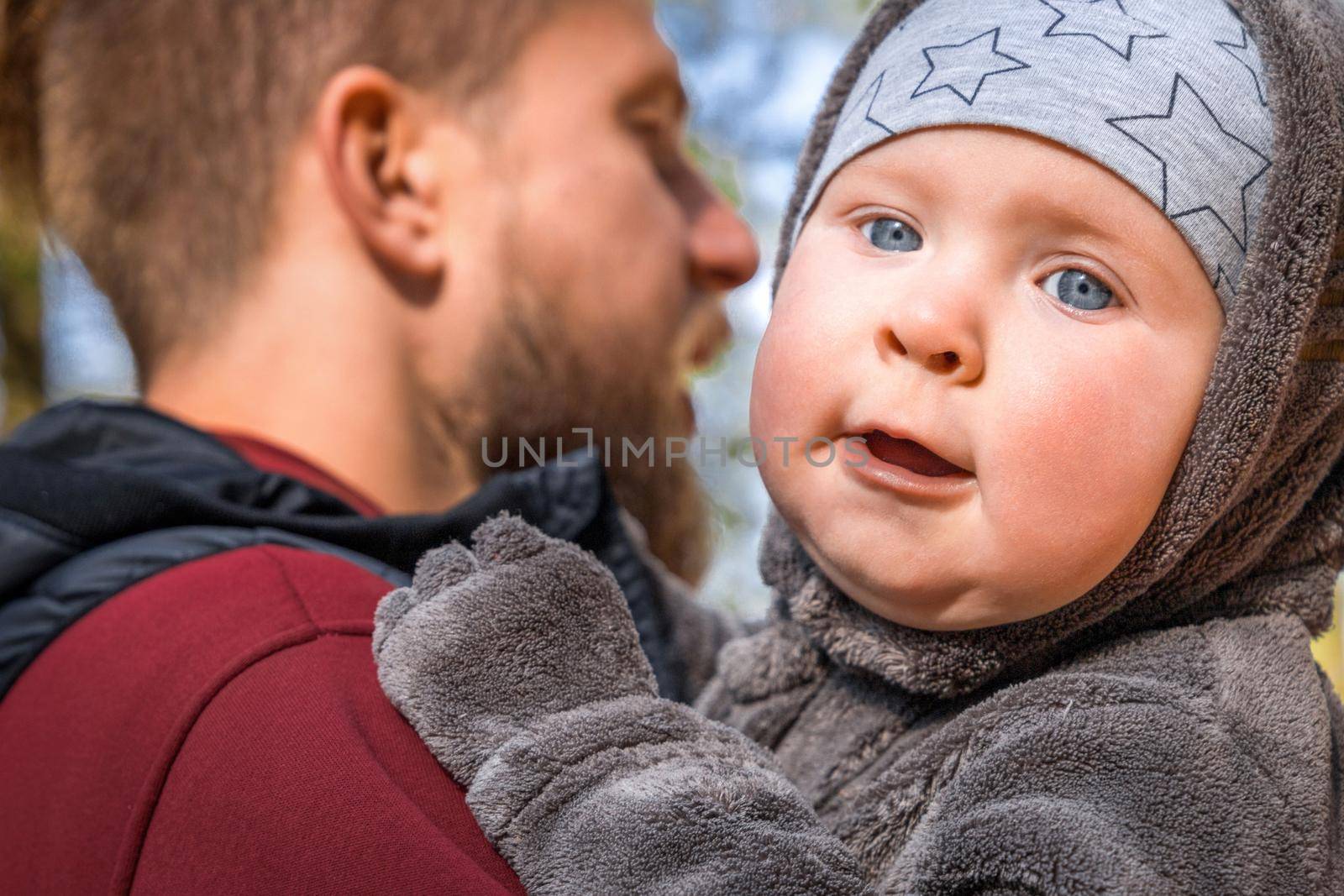 Close-up portrait of little baby boy in the arms of his father outdoor.