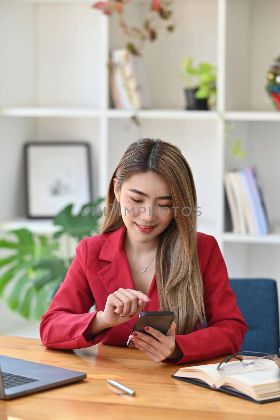 Portrait businesswoman using smart phone while sitting in office.