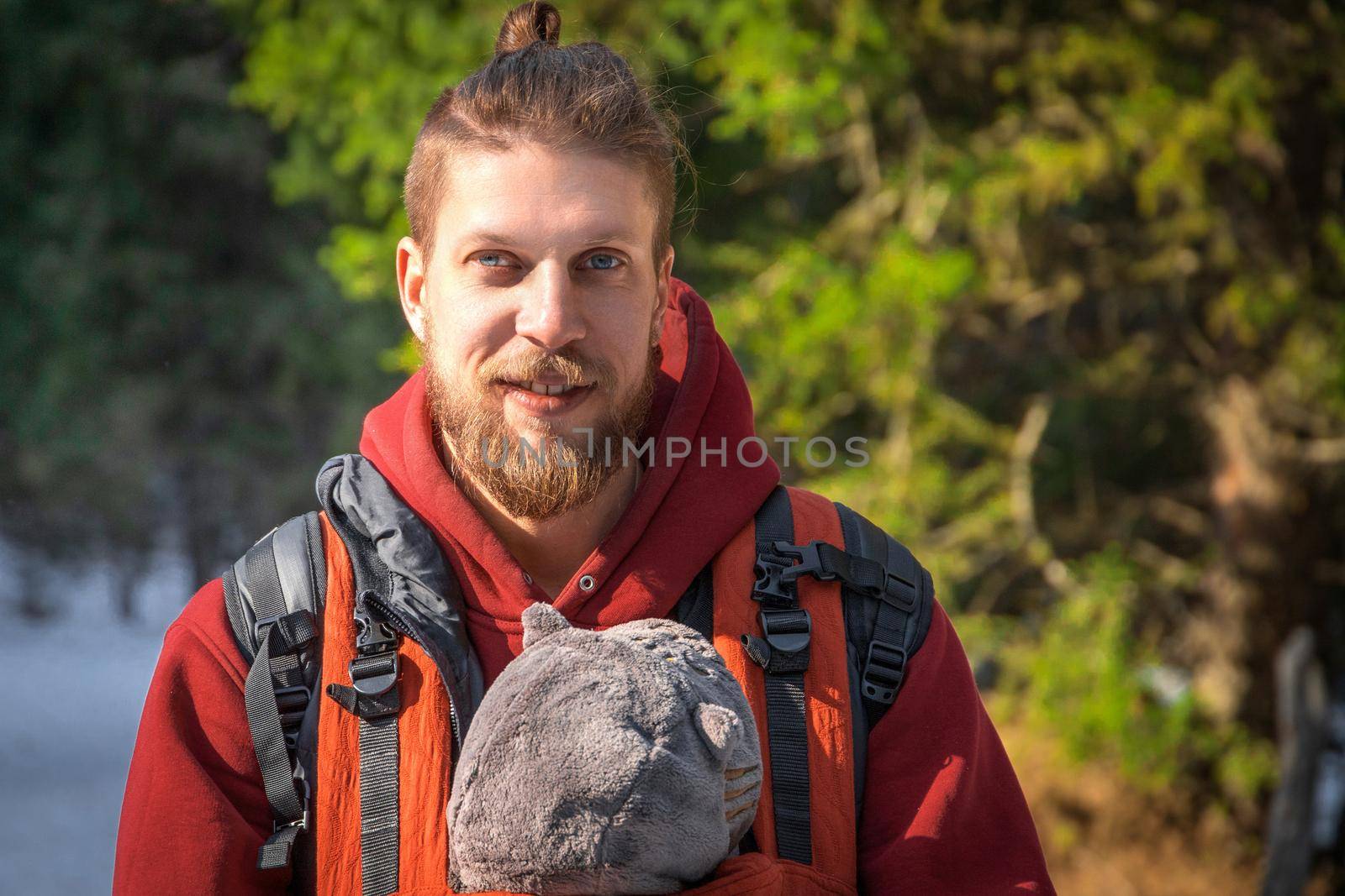 Portrait of bearded babywearing father with his son in baby carrier, family winter hiking.