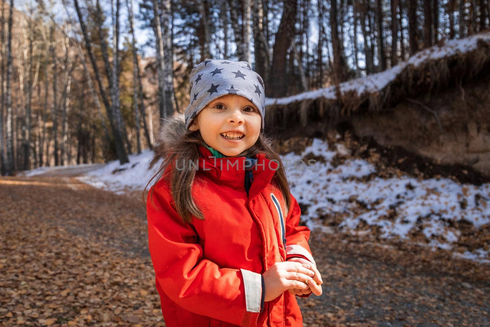 Joyful smiling happy preschool aged girl in red jacket in deep fall forest.