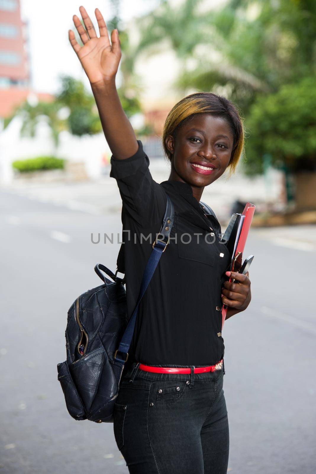 Young student standing in the street after class greeting with a smile.