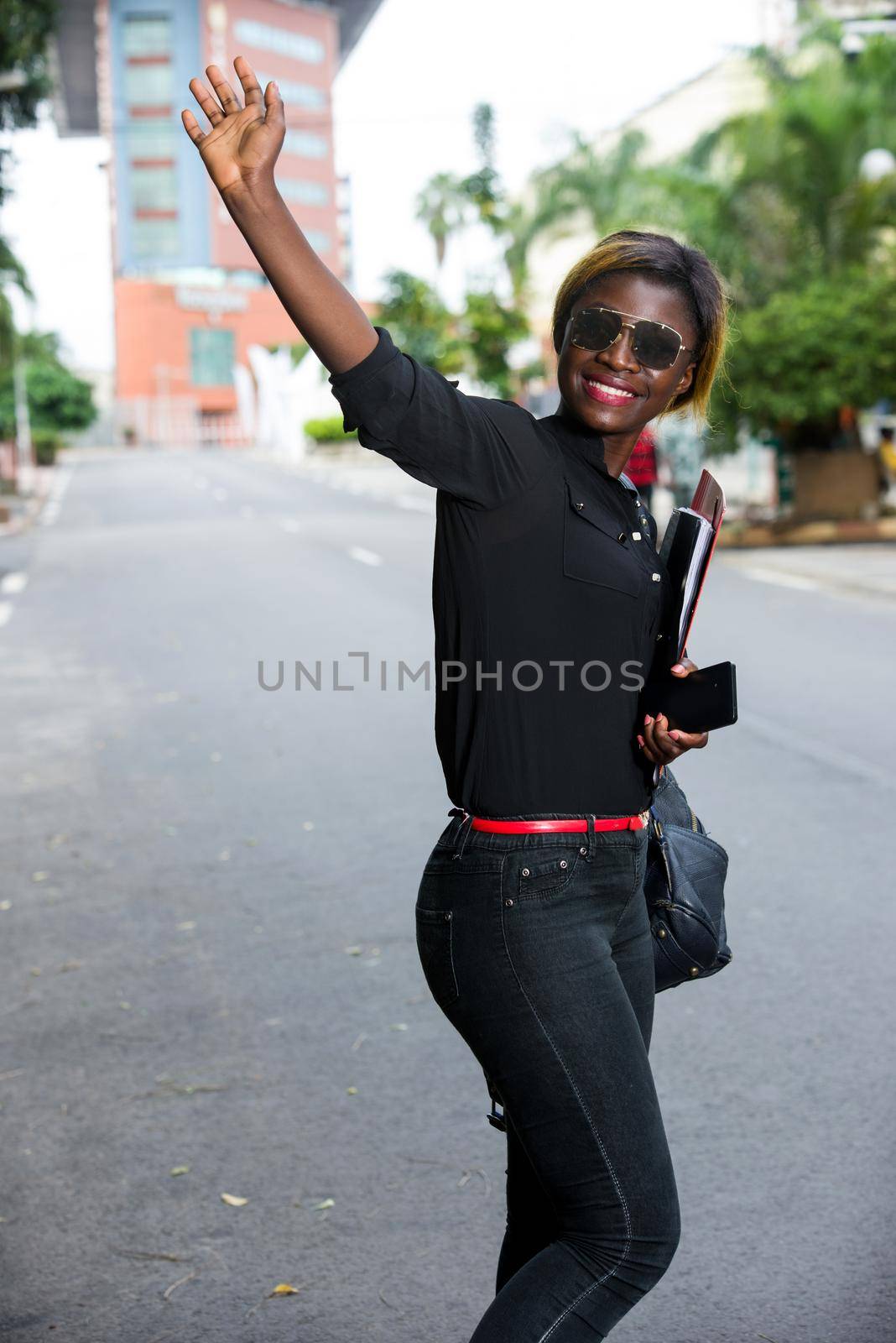 young student standing in glasses on the street after class greeting with a smile.