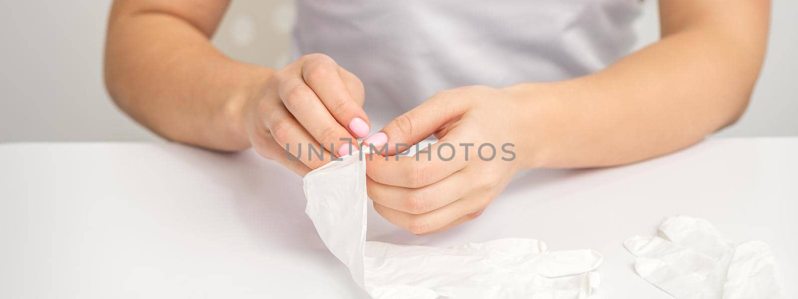 Close up of doctor hands puts on white latex gloves on the clean white table