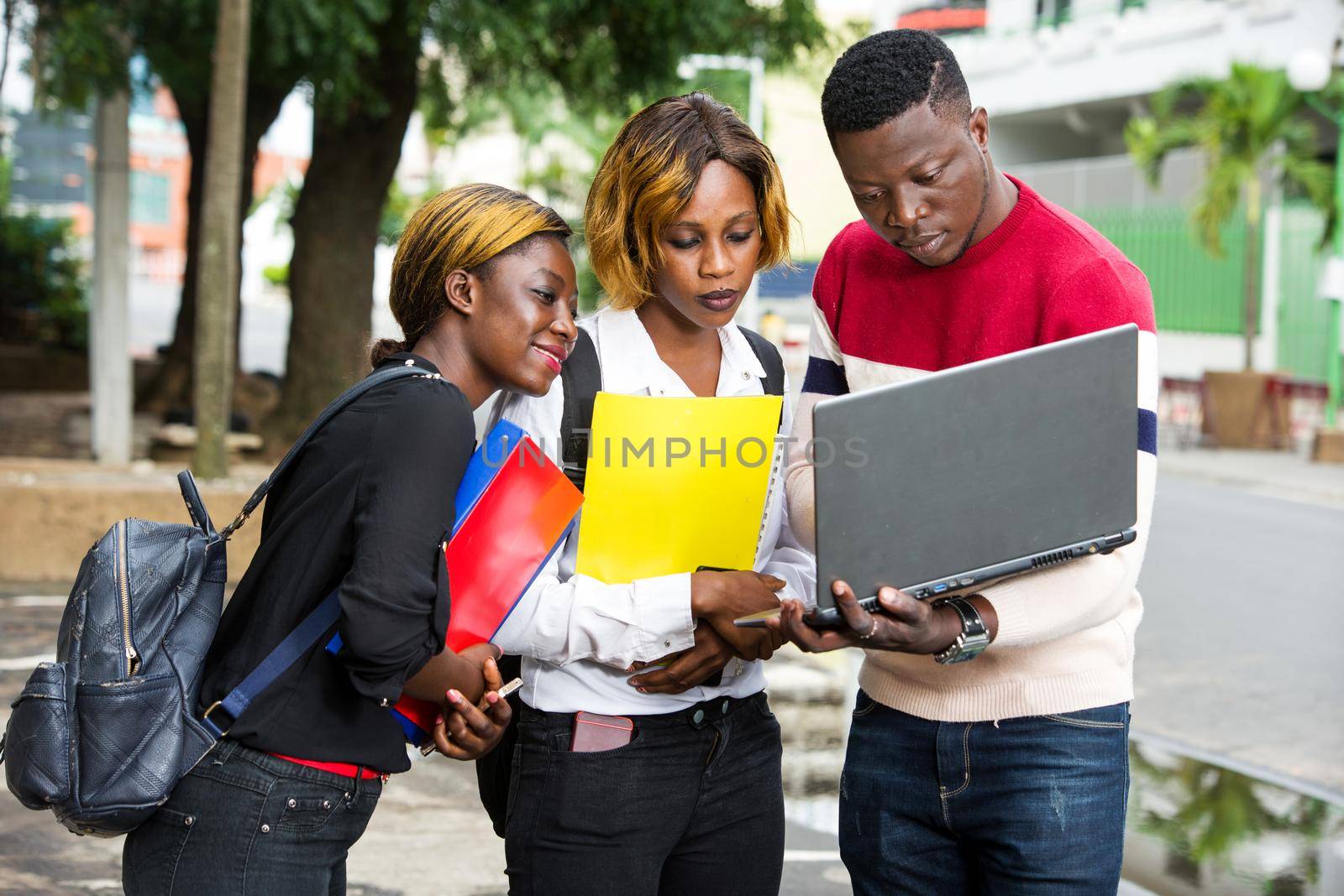 Students standing in the street after classes looking at laptop.