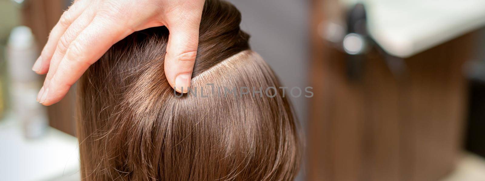 Hairdresser checks short brown hairstyle of a young woman in a beauty salon