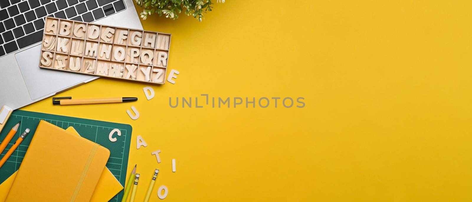 Top view laptop computer, potted plant and stationery on yellow background. by prathanchorruangsak