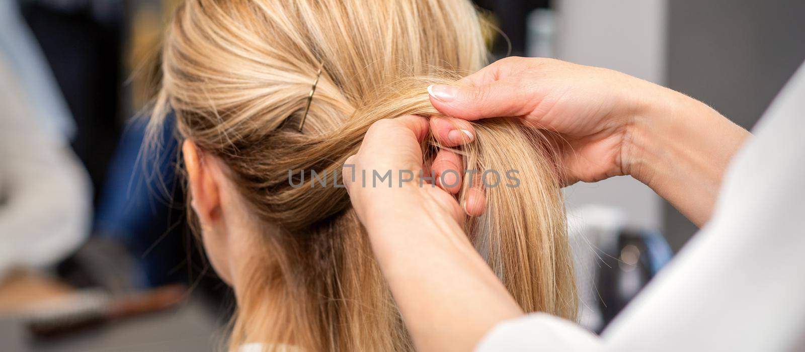Hairdresser's hands braiding client's hair by okskukuruza