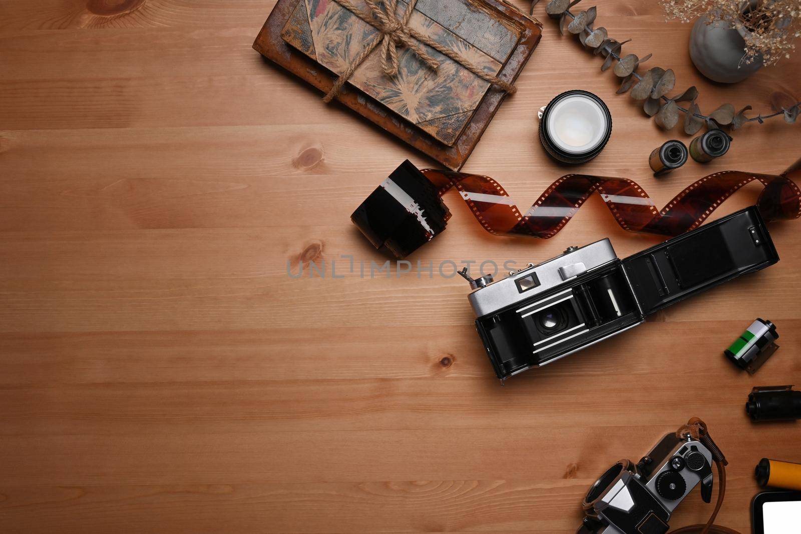 Top view film rolls, retro camera and book on wooden table. by prathanchorruangsak