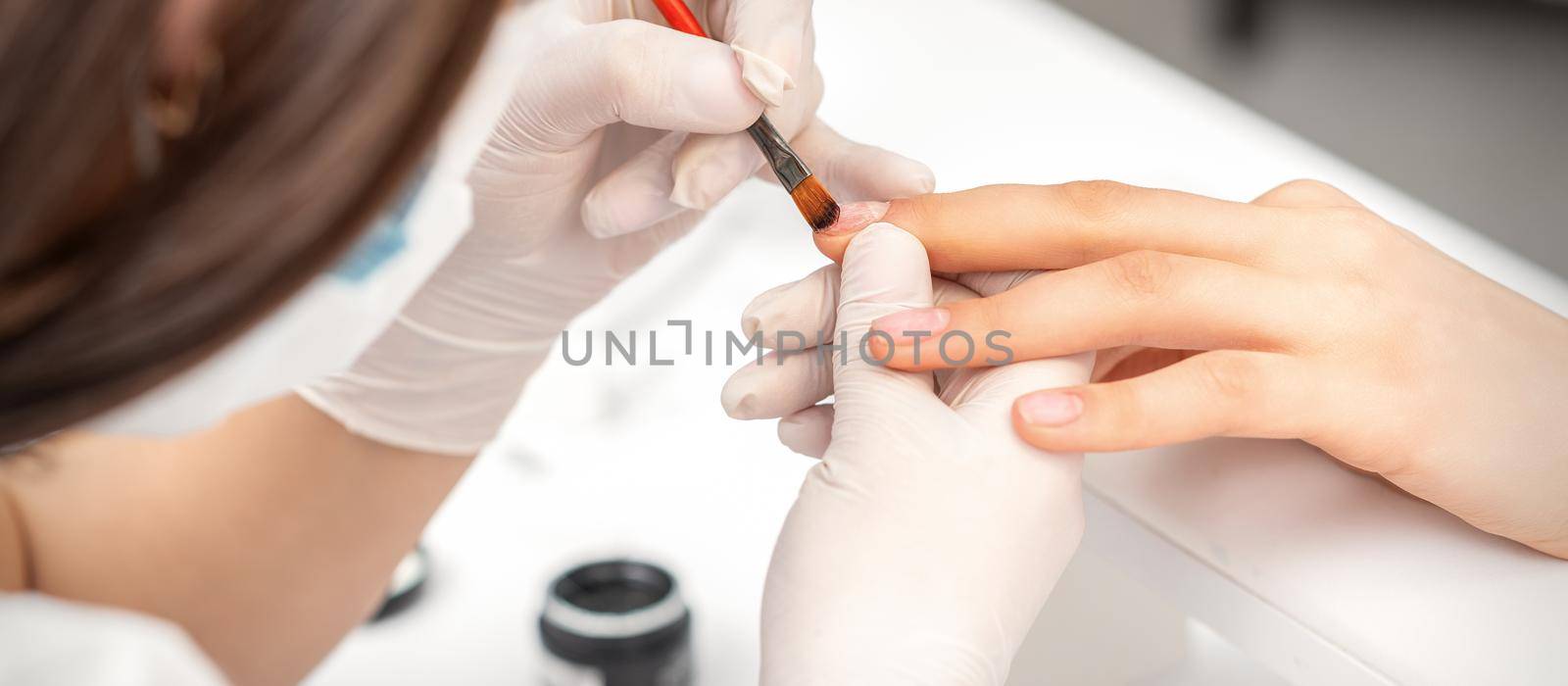 Manicurist covering nails with transparent polish by okskukuruza