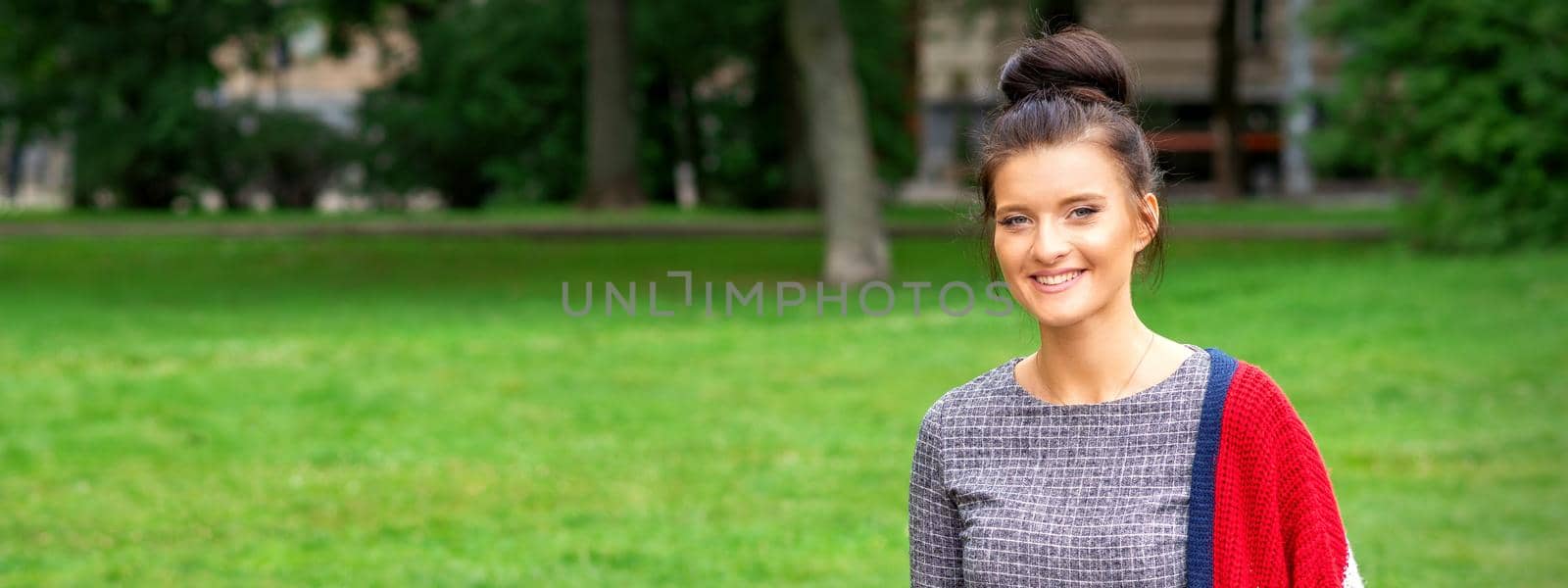 Portrait of a beautiful happy young woman in the park. Banner with copy space