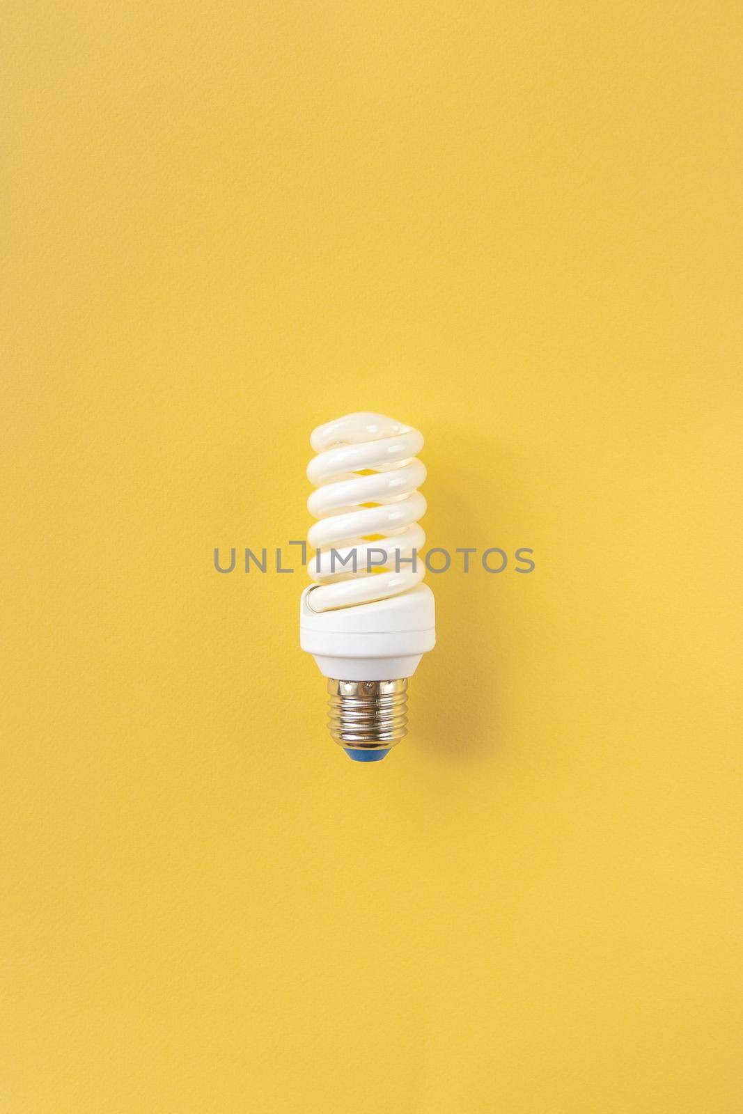 Energy saving light bulb on a yellow background. Economical consumption of electricity. The concept of nature conservation