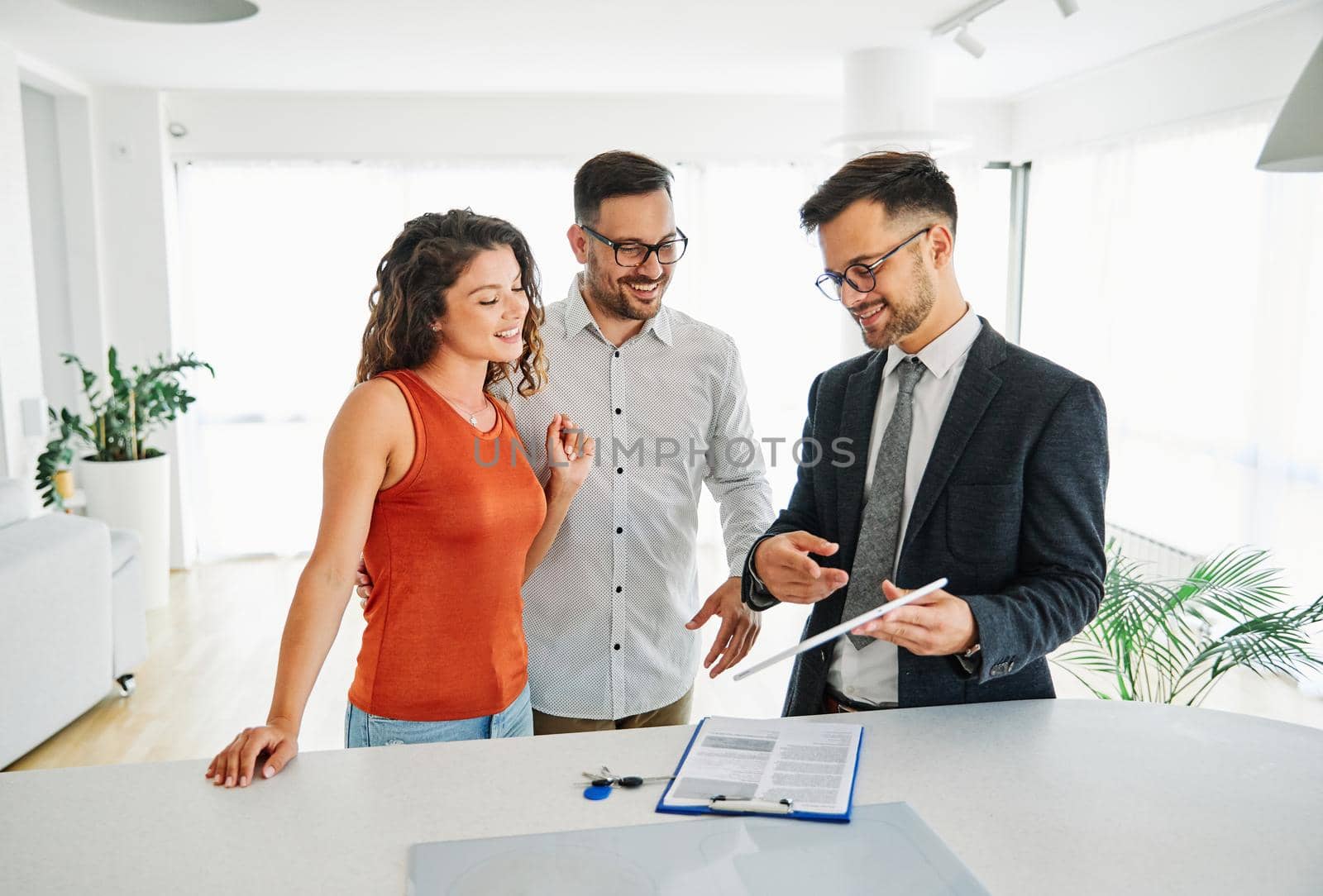 Young happy couple and an agent in a new property