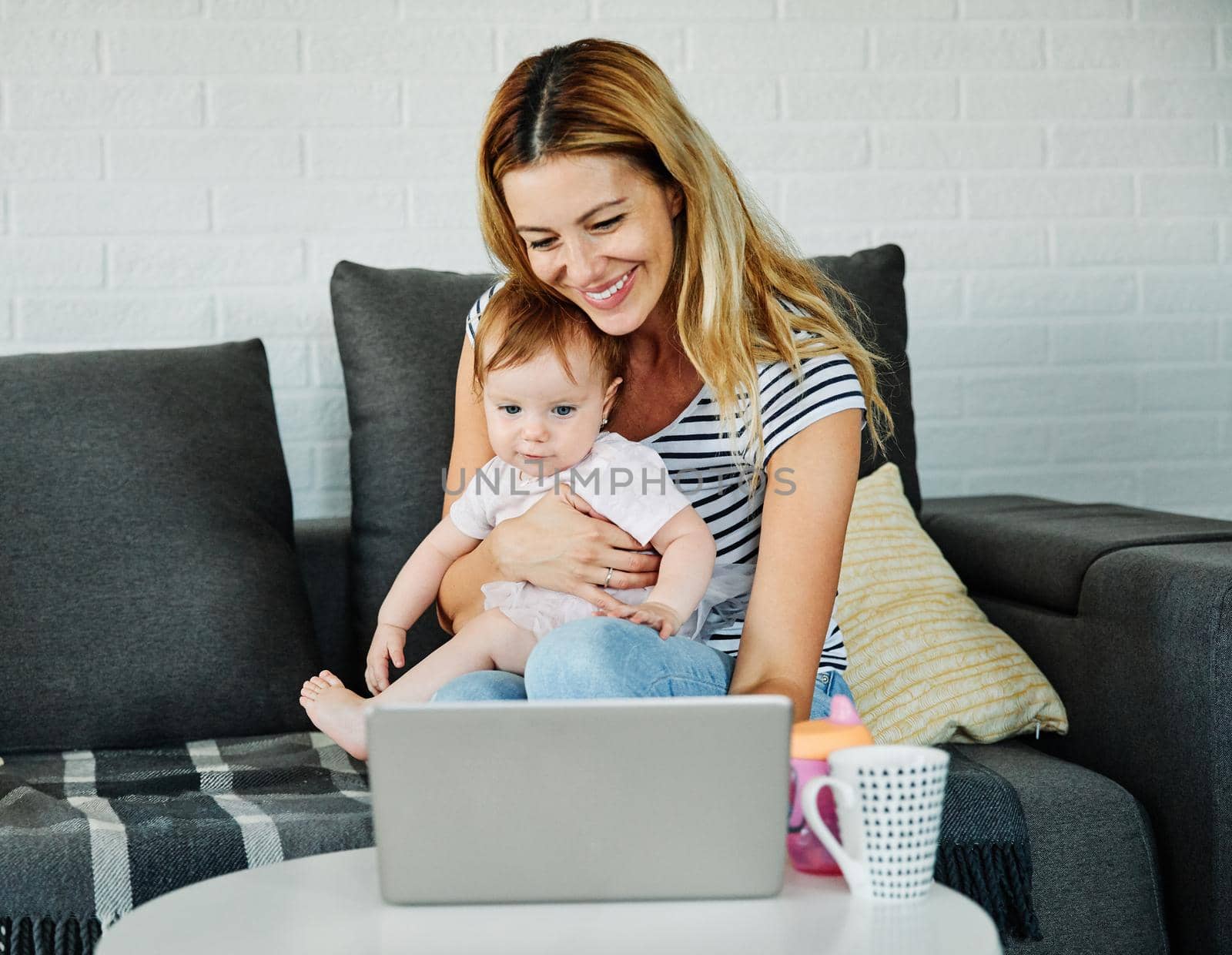 Busi working businesswoman mother and her baby daughter working on a laptop together at home